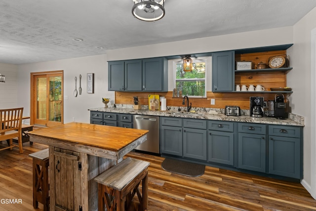 kitchen featuring sink, stainless steel dishwasher, dark hardwood / wood-style floors, a textured ceiling, and light stone counters