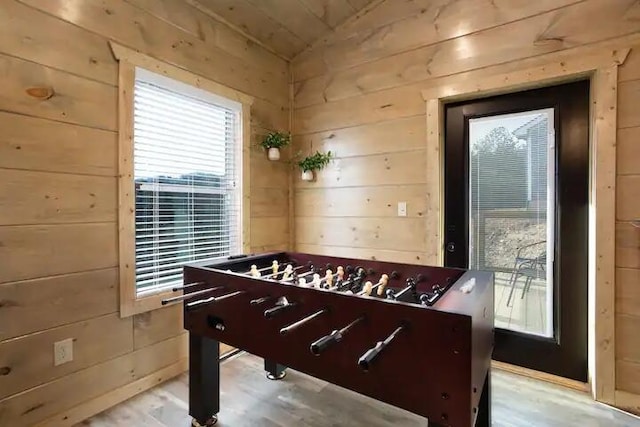 rec room with light wood-type flooring and wooden walls