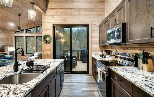 kitchen featuring wooden walls, stainless steel appliances, dark brown cabinets, a sink, and wooden ceiling
