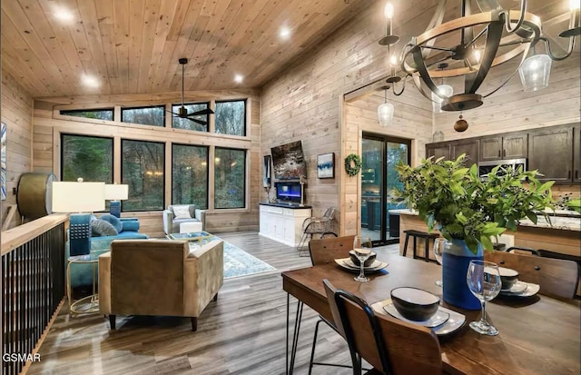 living room featuring wood walls, ceiling fan with notable chandelier, high vaulted ceiling, wood ceiling, and wood finished floors