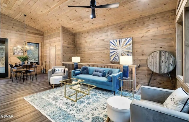 living room featuring wooden walls, wood finished floors, ceiling fan with notable chandelier, vaulted ceiling, and wooden ceiling