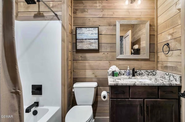 bathroom with vanity, toilet, wooden walls, and washtub / shower combination