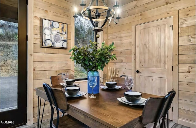 dining space featuring wood walls and a chandelier