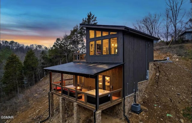 back of house at dusk with cooling unit and a deck
