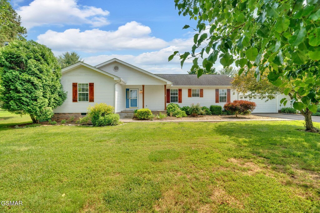 1647 Sams Dr, Dandridge, TN 37725 - ranch-style home featuring concrete driveway, a front yard, a garage, covered porch, and crawl space