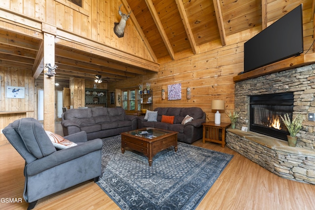 living room with a stone fireplace, wooden walls, ceiling fan, and wood ceiling