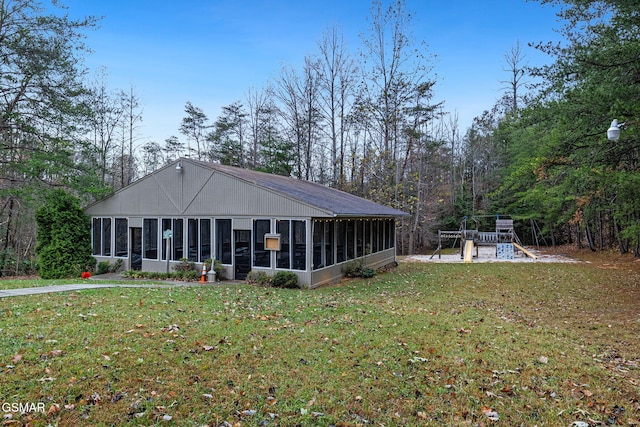 rear view of house featuring a playground, a sunroom, and a lawn