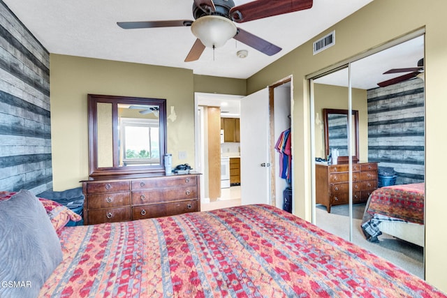 bedroom with ceiling fan, carpet floors, wooden walls, and a closet