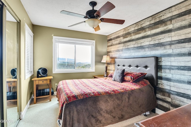 carpeted bedroom with ceiling fan and wooden walls