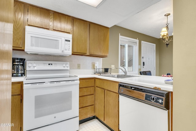 kitchen with pendant lighting, white appliances, and sink