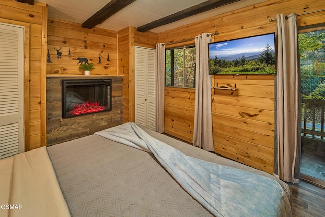 bedroom with beamed ceiling, access to outside, and wood walls