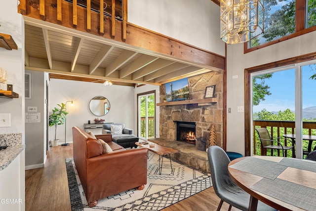 1452 N Arbon Ln, Gatlinburg, TN 37738 - living room featuring wood finished floors, beamed ceiling, a stone fireplace, a chandelier, and baseboards
