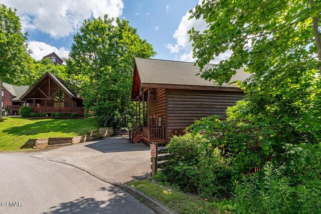 655 Stockton Dr, Sevierville, TN 37876 - view of side of home with a lawn, asphalt driveway, a patio, a shingled roof, and log veneer siding