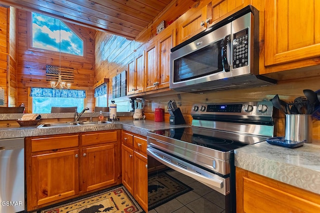 655 Stockton Dr, Sevierville, TN 37876 - kitchen featuring stainless steel appliances, a sink, brown cabinets, wood walls, and wooden ceiling