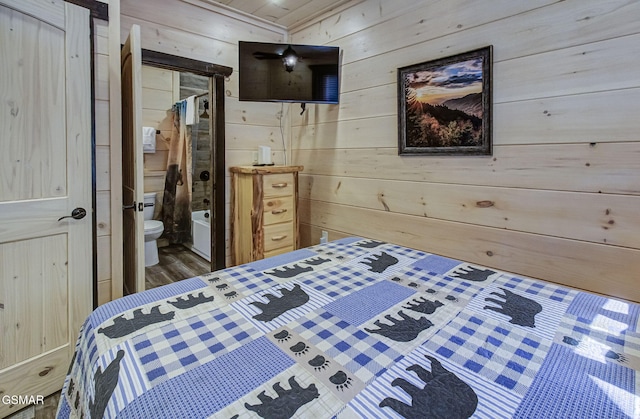 bedroom featuring ensuite bath, wooden walls, crown molding, and wood-type flooring