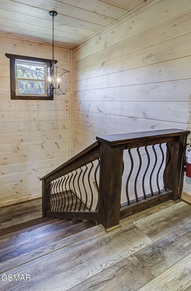 stairs featuring hardwood / wood-style floors, wood walls, wood ceiling, and a chandelier