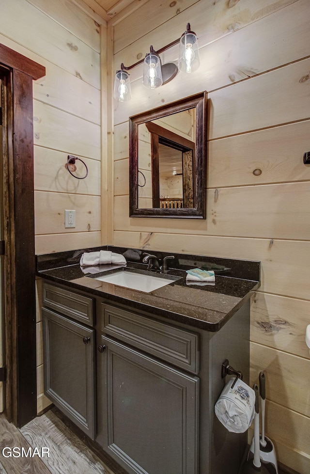 bathroom with hardwood / wood-style floors, vanity, and wooden walls