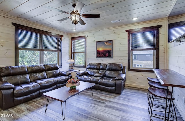 living room featuring ceiling fan, light hardwood / wood-style floors, wood ceiling, and wooden walls