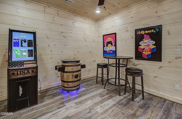 interior space featuring hardwood / wood-style flooring, ceiling fan, wood walls, and wooden ceiling