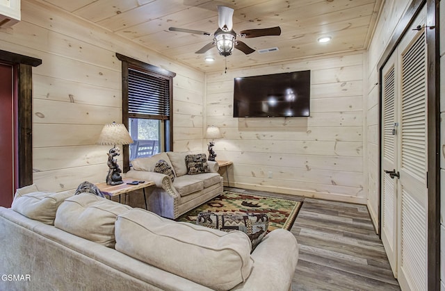 living room featuring wood-type flooring, ceiling fan, wooden ceiling, and wood walls