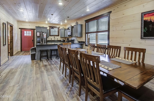 dining space with wood-type flooring, sink, wooden walls, and wood ceiling