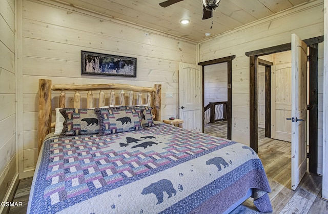 bedroom featuring ceiling fan, wood-type flooring, wooden walls, and wooden ceiling