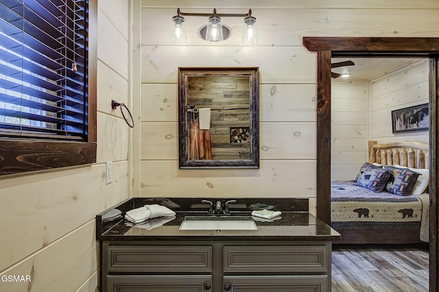 bathroom with hardwood / wood-style flooring, vanity, and wooden walls