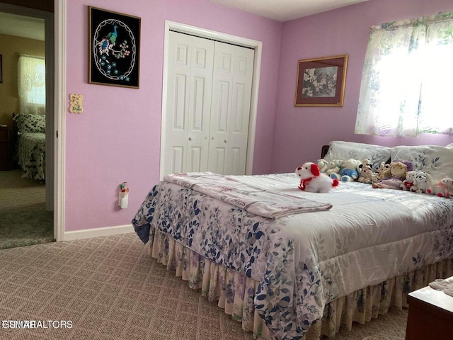 carpeted bedroom with a closet and baseboards