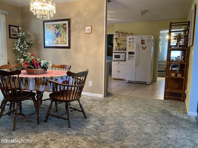 dining space featuring a chandelier, light colored carpet, light tile patterned flooring, and baseboards