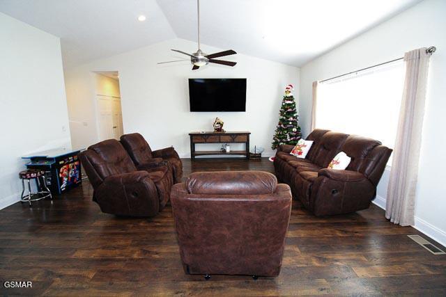 living room with ceiling fan, dark hardwood / wood-style flooring, and lofted ceiling