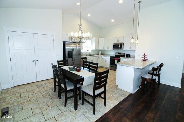 dining area with sink, high vaulted ceiling, and an inviting chandelier