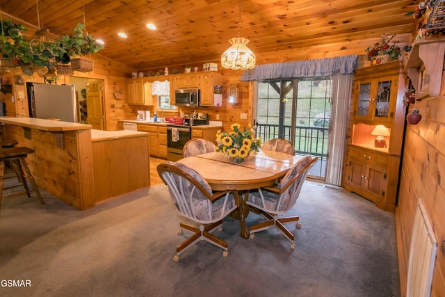 dining space featuring lofted ceiling, wooden ceiling, light carpet, sink, and wooden walls