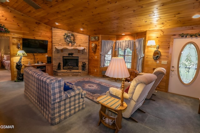 carpeted living room featuring lofted ceiling, wood ceiling, a fireplace, and wooden walls