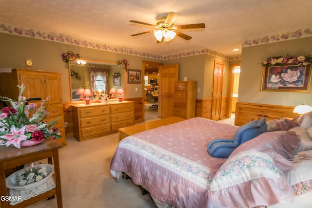 bedroom with ceiling fan, a closet, light carpet, and wooden walls