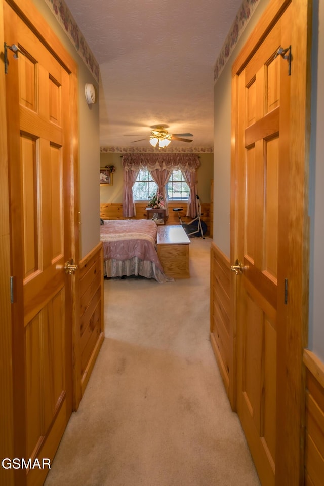 bedroom with ceiling fan, light colored carpet, and wood walls