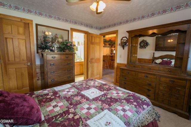 carpeted bedroom featuring connected bathroom, ceiling fan, and a textured ceiling