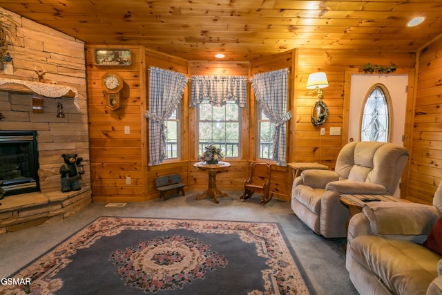 living room featuring a fireplace, carpet floors, wooden walls, and wood ceiling