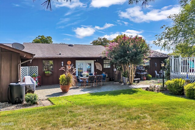 back of property with a yard and a patio area