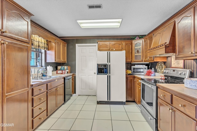 kitchen featuring sink, light tile patterned floors, stainless steel appliances, and a textured ceiling