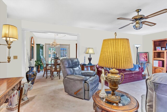 carpeted living room featuring ceiling fan with notable chandelier