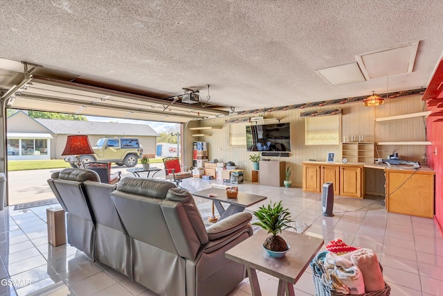 living room featuring light tile patterned floors, wooden walls, a textured ceiling, and a healthy amount of sunlight