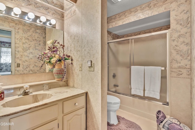 full bathroom featuring vanity, tile patterned floors, bath / shower combo with glass door, toilet, and a textured ceiling