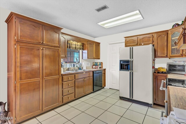 kitchen with dishwasher, sink, white refrigerator with ice dispenser, light tile patterned floors, and range