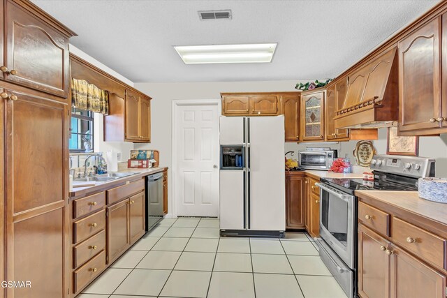 kitchen featuring dishwasher, white refrigerator with ice dispenser, sink, light tile patterned floors, and stainless steel electric range oven