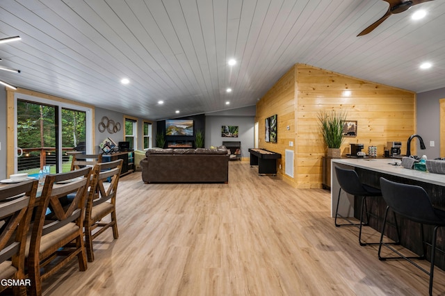 living area featuring light wood-style flooring, recessed lighting, wood ceiling, vaulted ceiling, and a lit fireplace