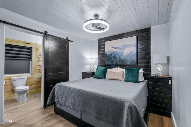 3033 N Clear Fork Rd, Sevierville, TN 37862 - bedroom featuring wooden walls, a barn door, wood finished floors, and ensuite bath