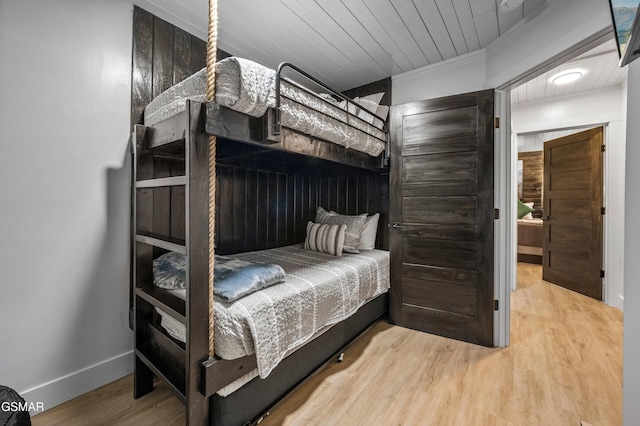 bedroom with wooden ceiling, baseboards, and wood finished floors