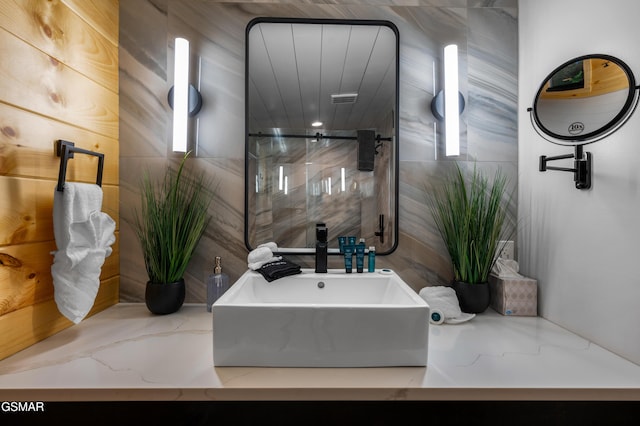 bathroom featuring a shower with door and a sink