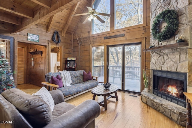 living room featuring a fireplace, wood-type flooring, visible vents, wooden walls, and wooden ceiling