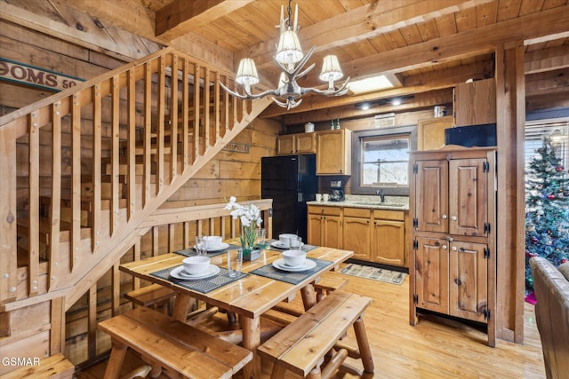 dining space with wooden ceiling, wooden walls, light wood-type flooring, beam ceiling, and an inviting chandelier